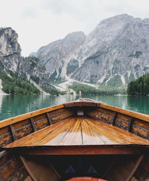 brown wooden boat moving towards the mountain