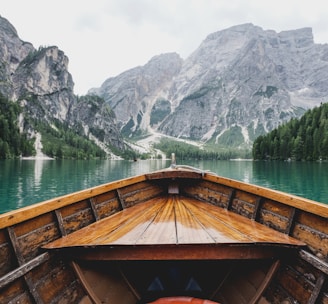 brown wooden boat moving towards the mountain