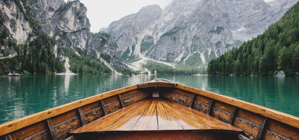 brown wooden boat moving towards the mountain