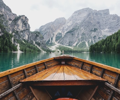 brown wooden boat moving towards the mountain