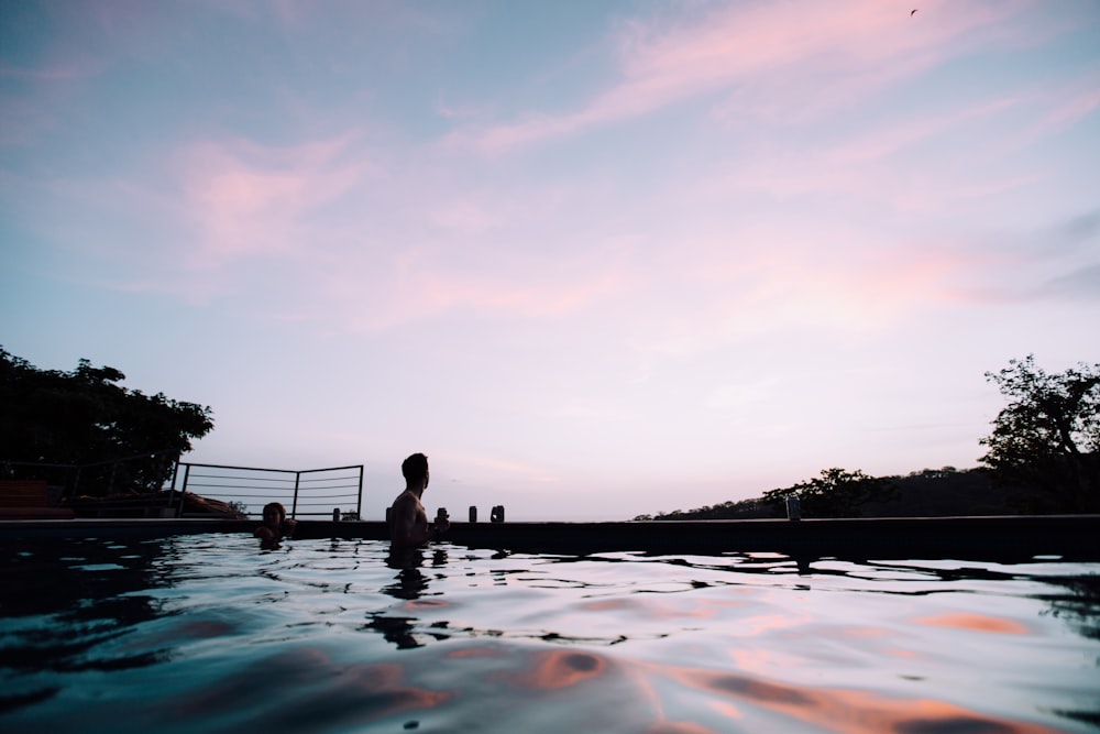 people swimming at pool under blue sky and white clouds during daytime