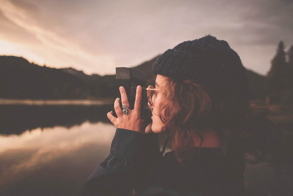 photograph of woman taking a picture of body of water