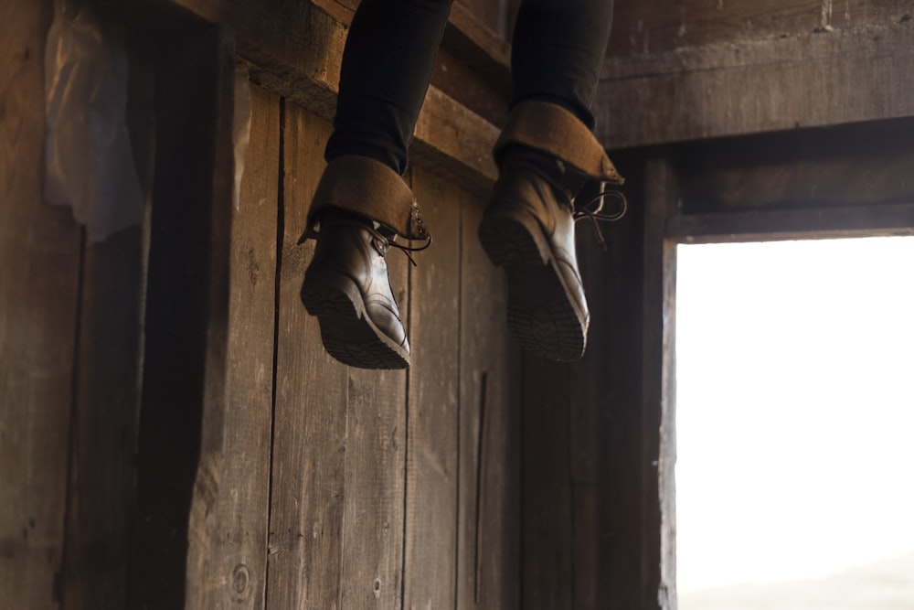 pieds de personne avec des bottes en cuir marron qui pendent à l’entrée