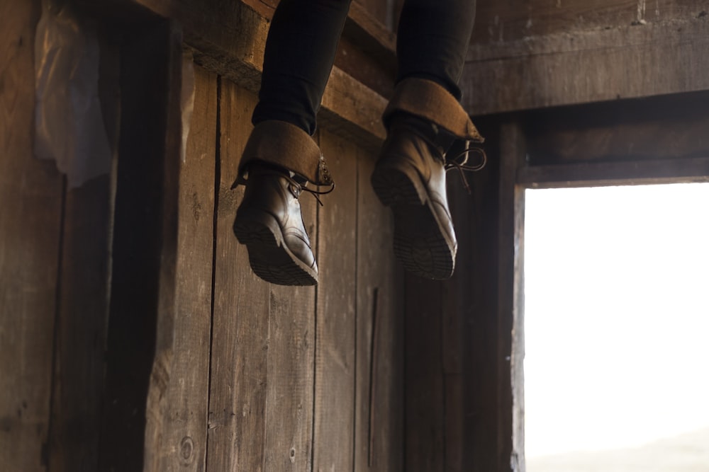 person feet with brown leather boots dangling by the entrance