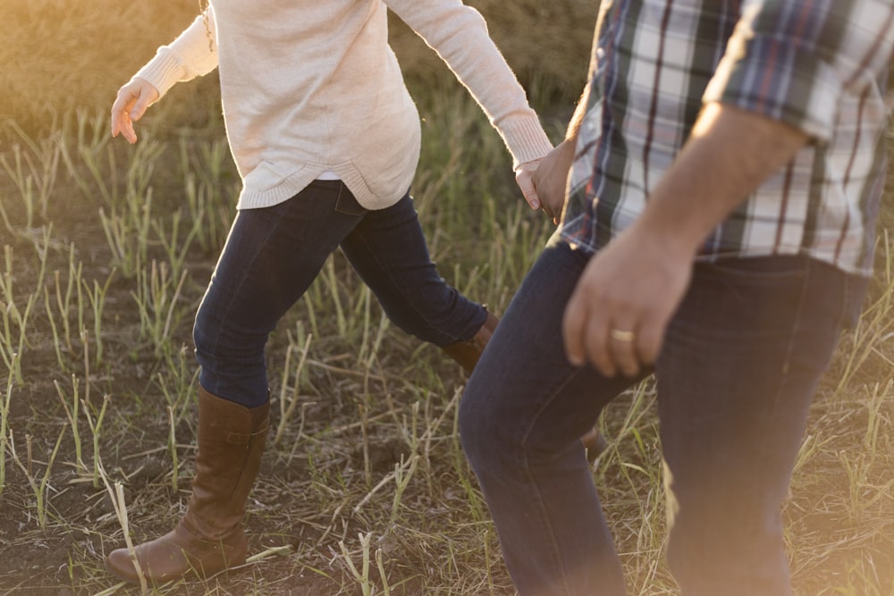 Dos personas con pantalones de mezclilla en el campo de césped