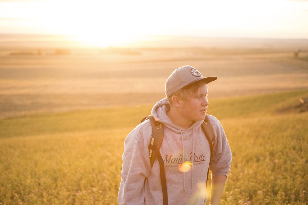 man wearing gray pullover hoodie near green grass at daytime