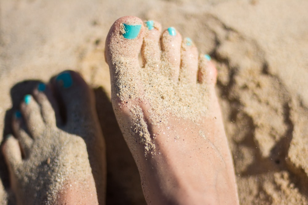 person sky-blue nail polish feet on brown sand