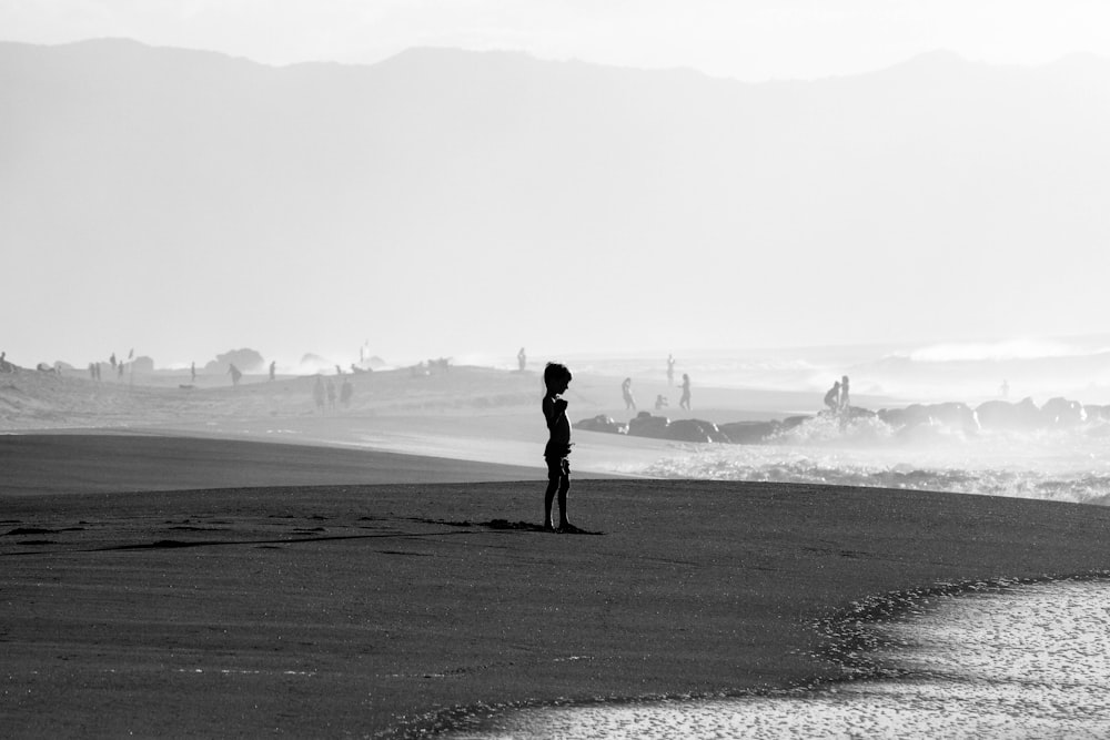 grayscale photo of man walking on beach