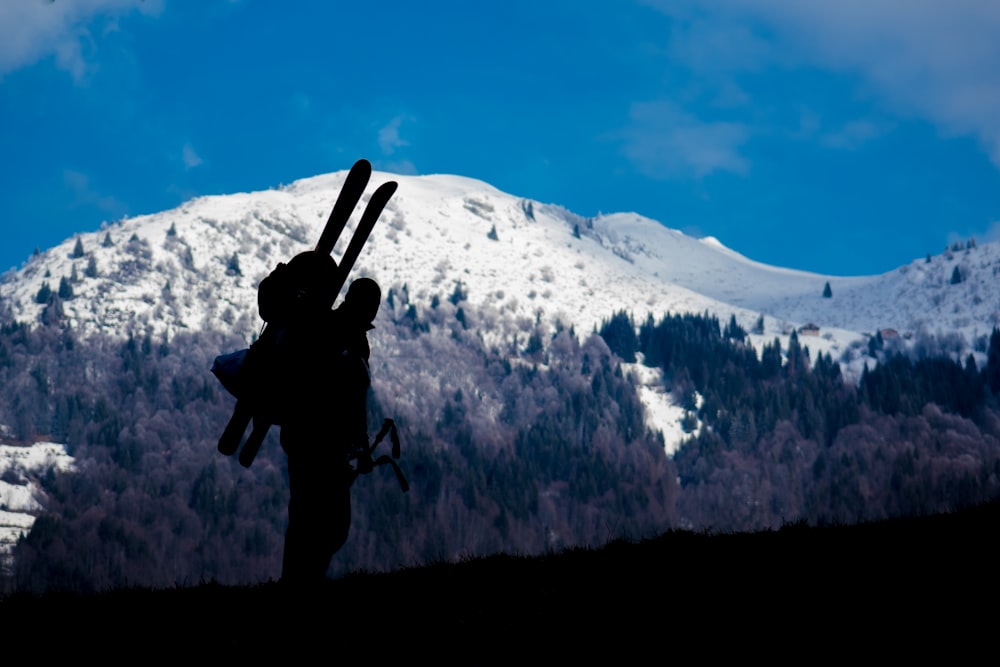 Silhouette of a skier ascending a snowy blue mountain landscape