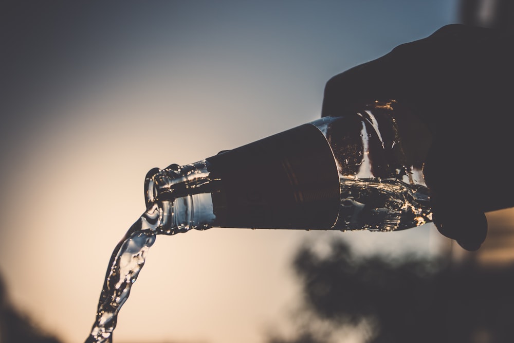 personne verse une bouteille d’eau