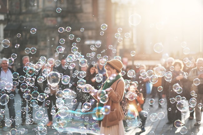 Jovem mulher expressando alegria na rua envolvida por bolhas de sabão