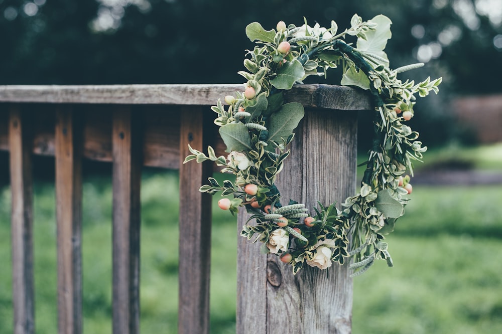 photo of green flower wreath hang on gray wooden baluster outdoors during daytime