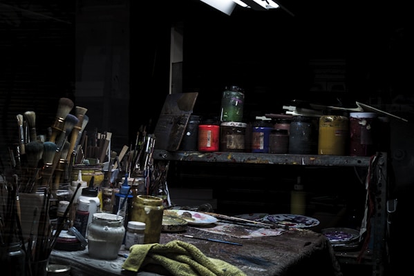 An artist's workspace featuring brushes, paints, and a half-finished canvas glowing under soft natural light.