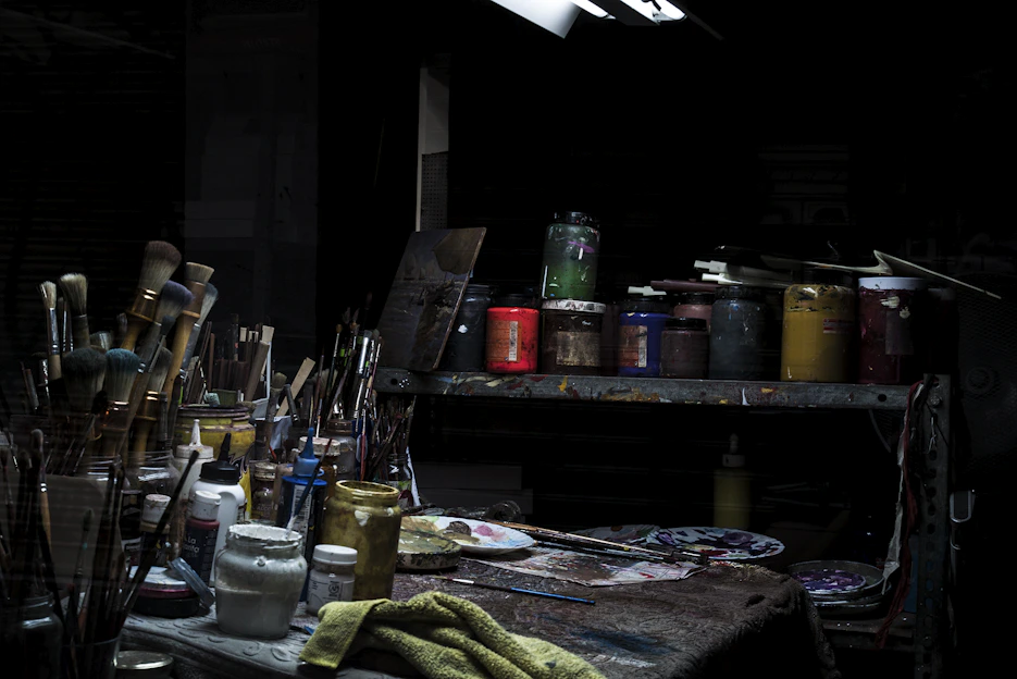 A bright, inviting workspace with paintbrushes, colourful paints, and sketchpads neatly arranged on a wooden table.