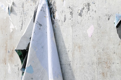 Close-up of a textured wall with layered posters and peeling paint, evoking urban memory.