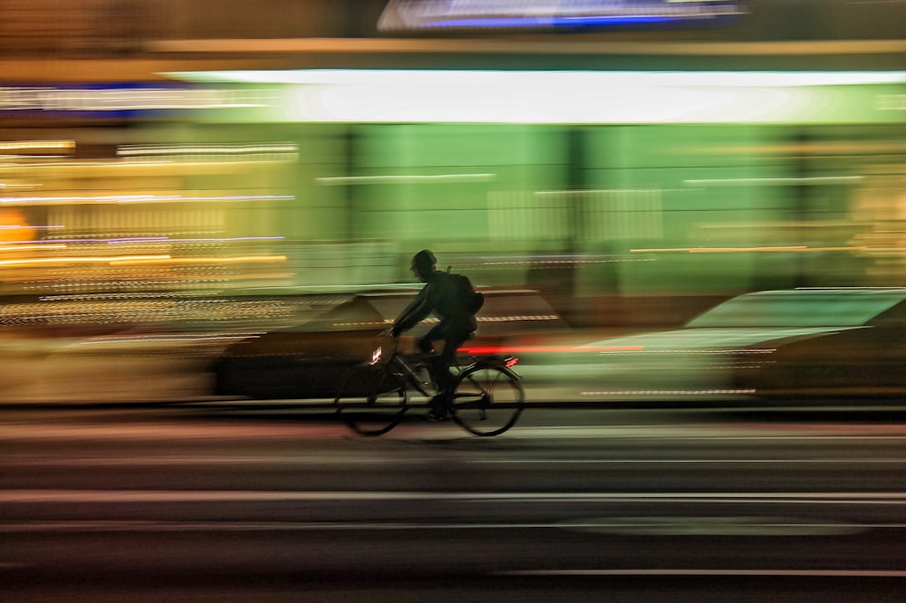 time lapse photo of person riding bicycle on road