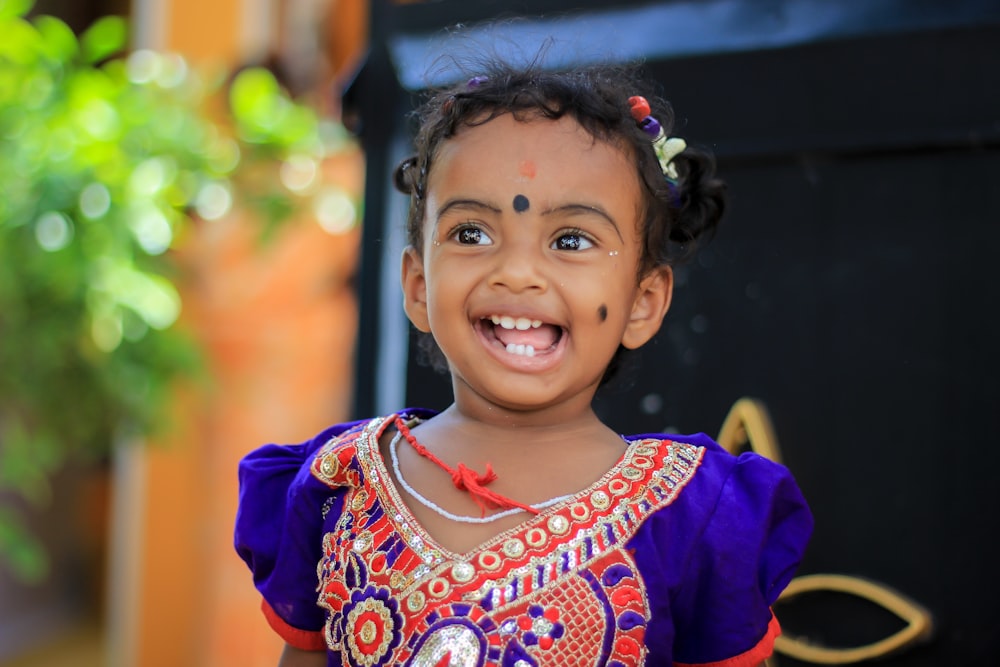 Fotografia de foco seletivo da menina sorrindo enquanto está perto da planta durante o dia