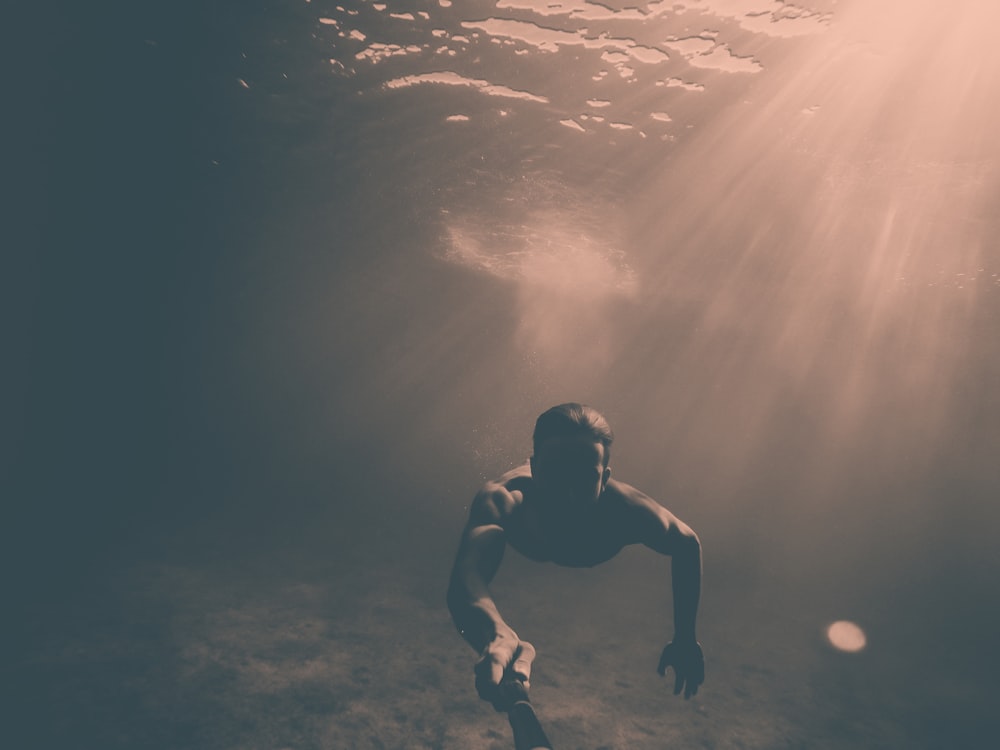 Hombre sosteniendo un monopié negro mientras está bajo el mar