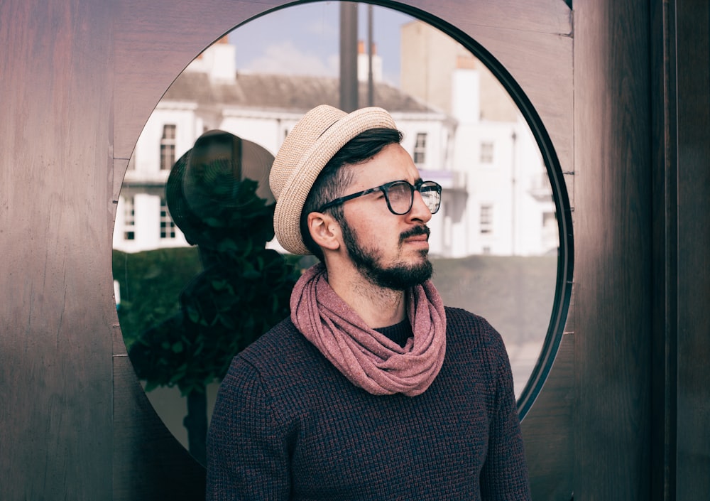 man wearing eyeglasses and black shirt leaning on glass door while looking up