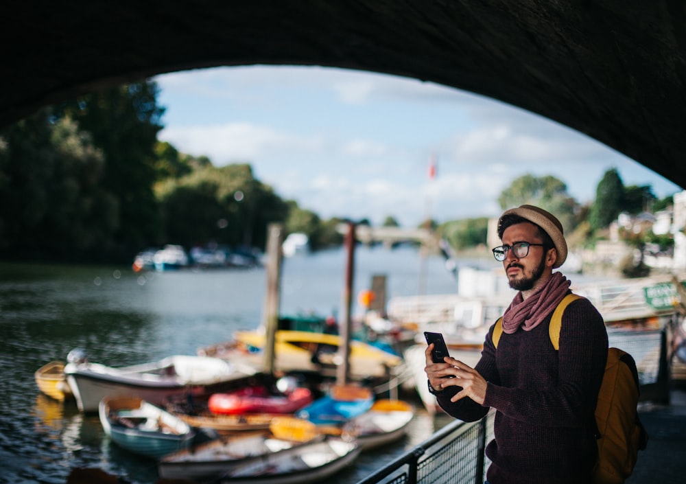 man holding phone under bridge