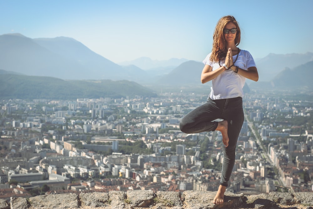 Una mujer meditando al aire libre, con vistas a la ciudad.