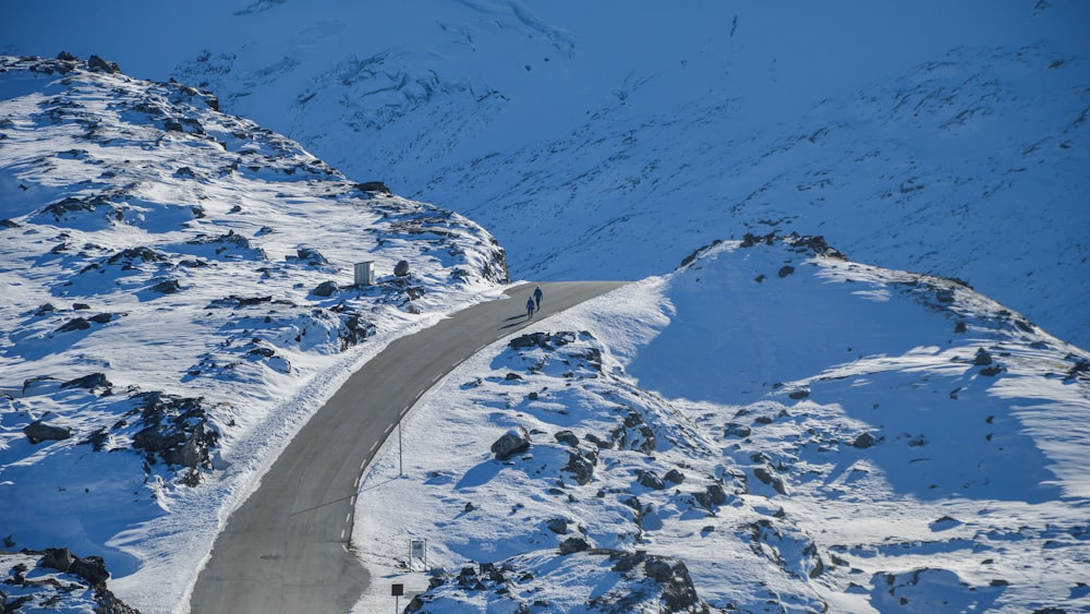 bird's eye photography of two people walking on road between snowfield