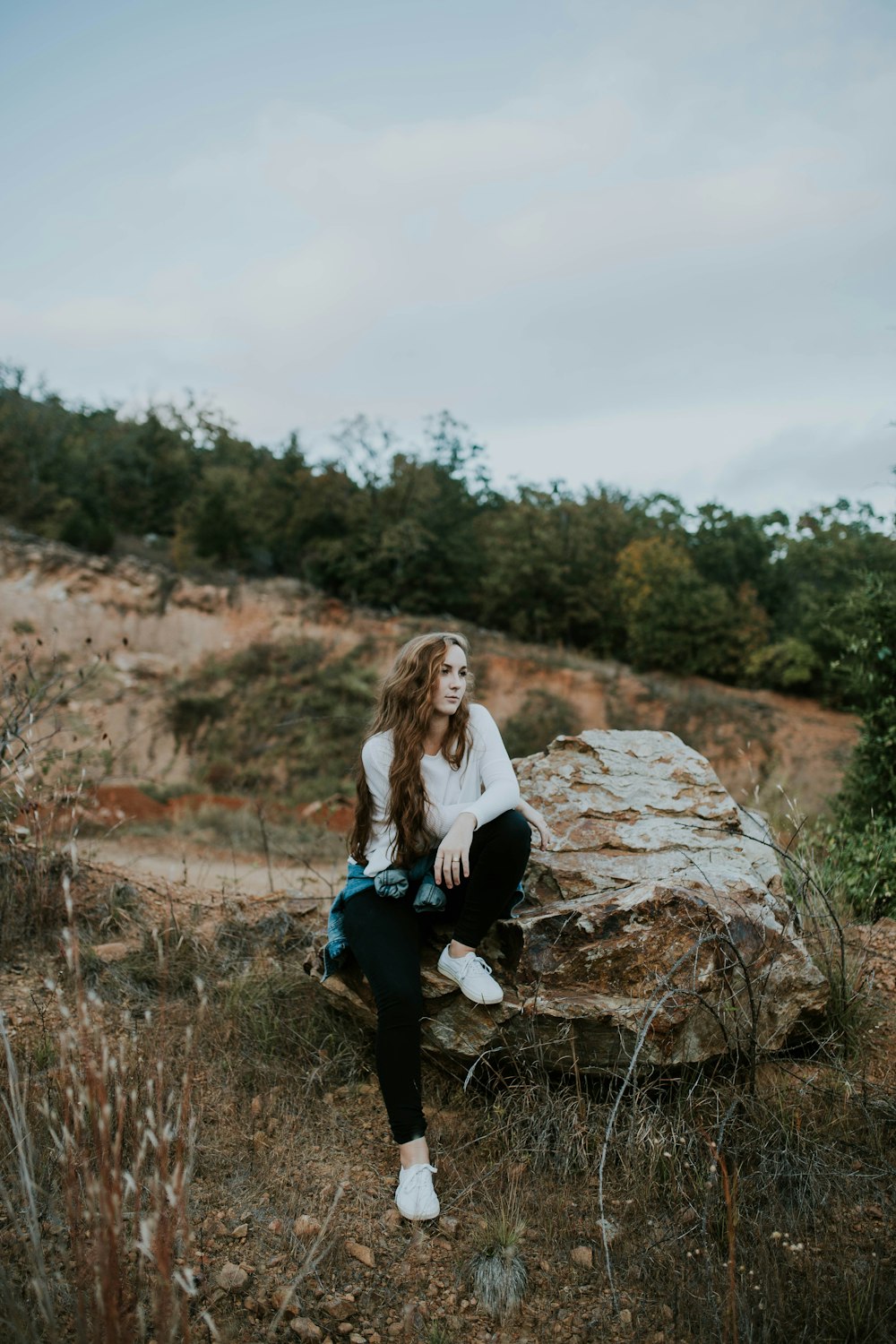 屋外の石の岩の上に座っている女性
