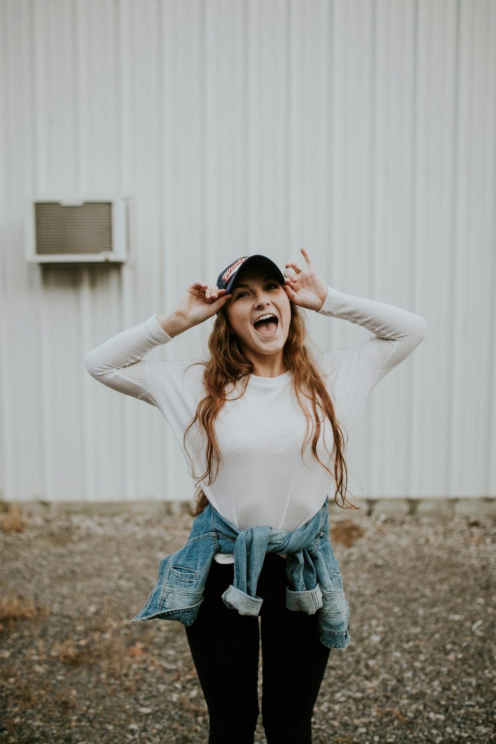 woman wearing black cap standing outside the house while laughing