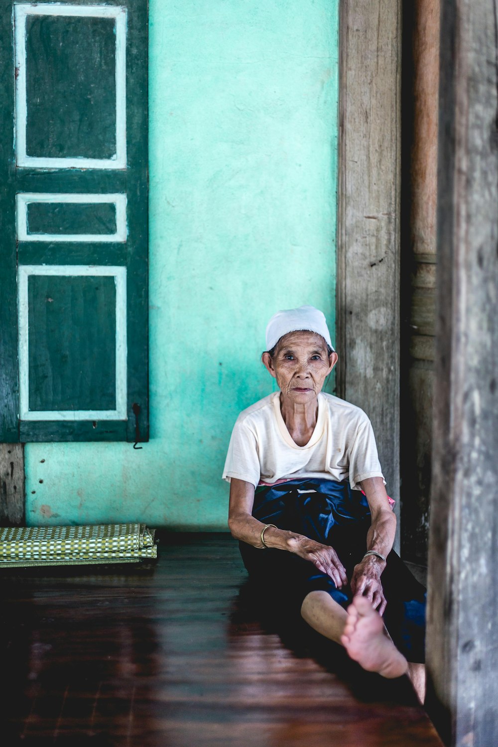 woman sitting on floor with leaning on teal painted wall