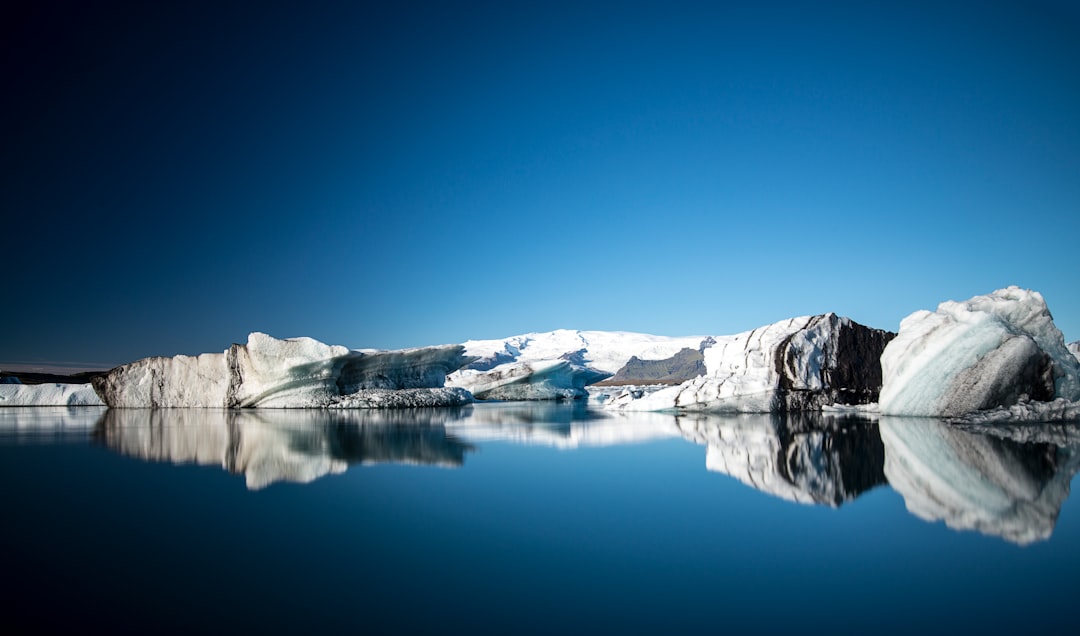 black mountain covered by snow near body of water during daytime