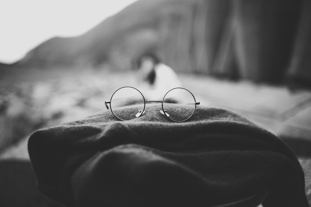 Foto in scala di grigi di occhiali hippie su stoffa