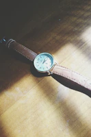 Classic analog watch with leather strap resting on a wooden table.