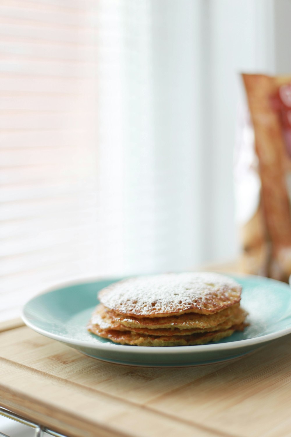 selective focus photography of four piece pancakes with powdered sugar on top in blue ceramic plate