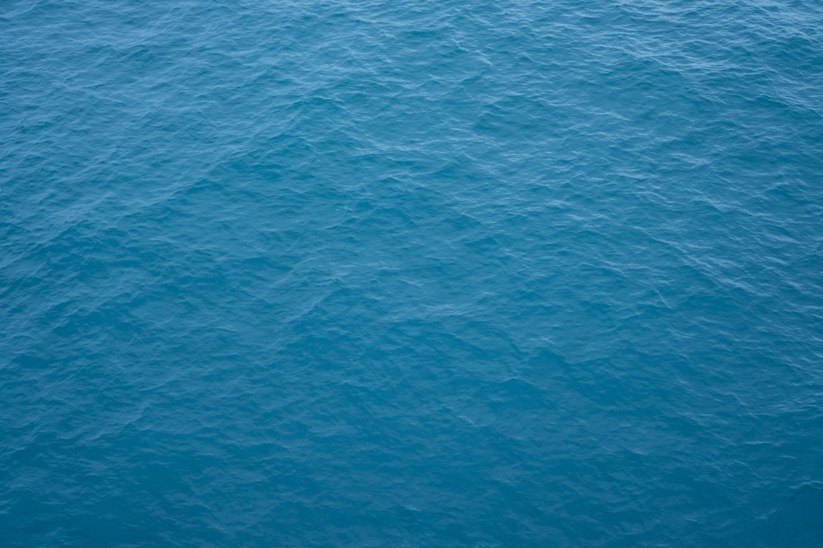 Aerial view of textured teal ocean water and foam.