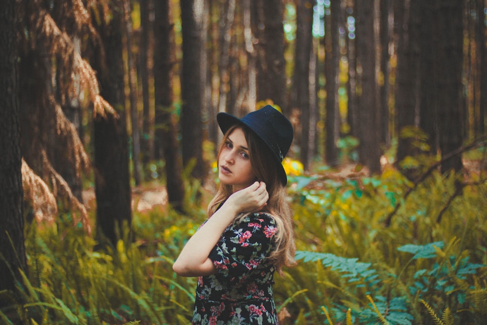 femme debout près de l’herbe verte et des arbres pendant la journée