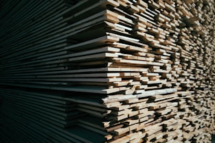 A close-up of sturdy wooden planks stacked neatly in a sunlit warehouse.