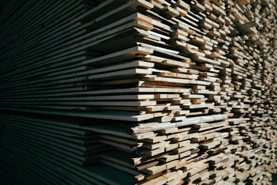 A stack of sturdy wooden planks neatly arranged in a sunlit warehouse.