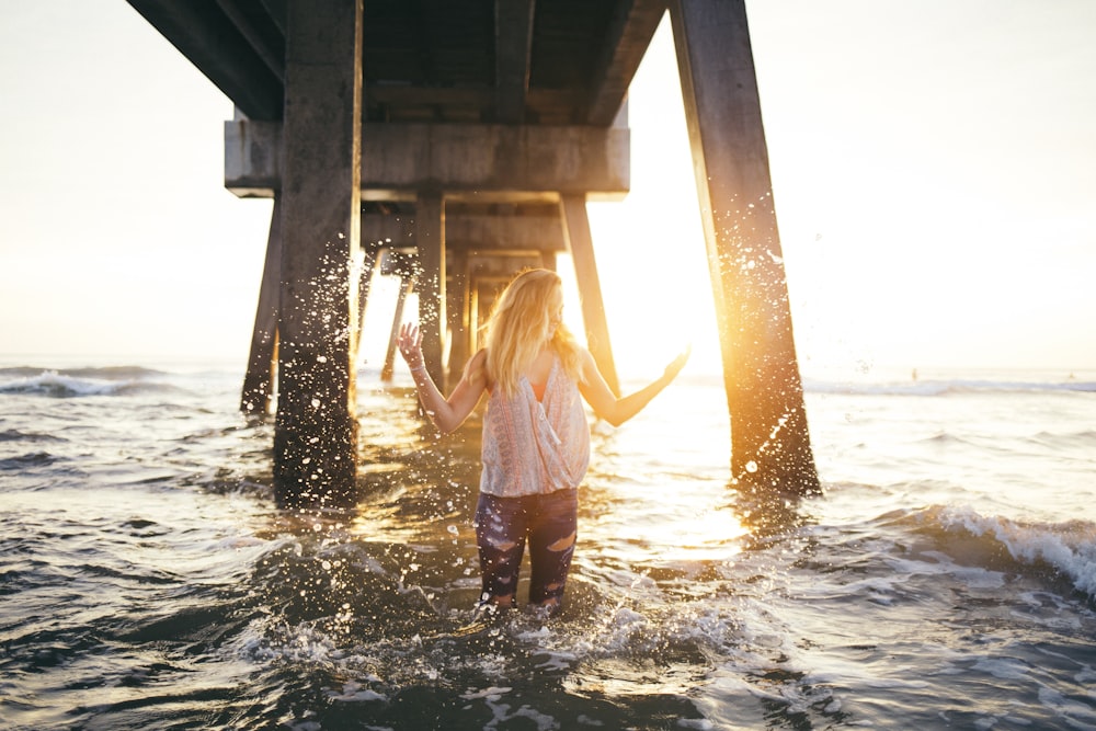 woman stading in water under a dock during golden time