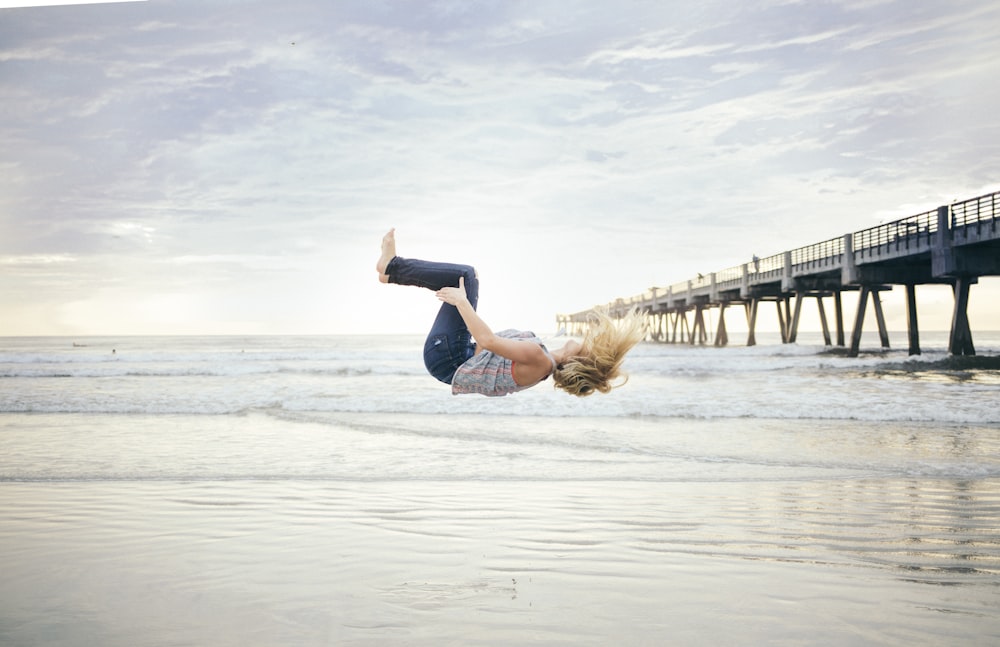 woman doing a back flip on beachshore