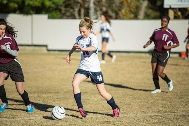 Close-up of a player skillfully dribbling the ball past opponents on a lush green pitch
