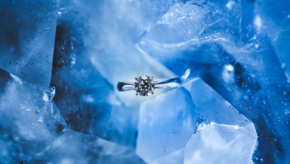 anel prateado com pedra preciosa clara dentro do gelo