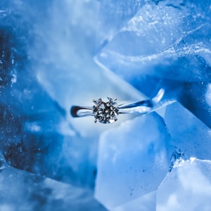 silver-colored ring with clear gemstone inside ice