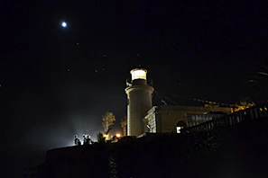 Minimalist lighthouse logo illuminated against a soft night sky