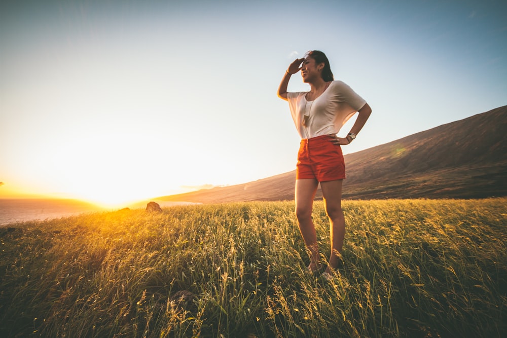 woman in beige batwing sleeved shirt and red shorts standing on grass field