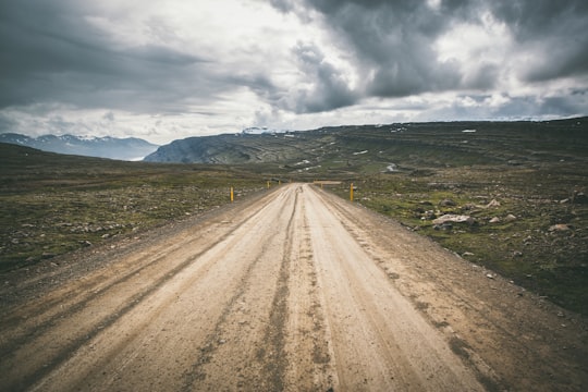brown concrete road under cloudy sky in Egilsstaðir Iceland