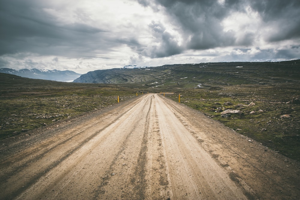 brown concrete road under cloudy sky