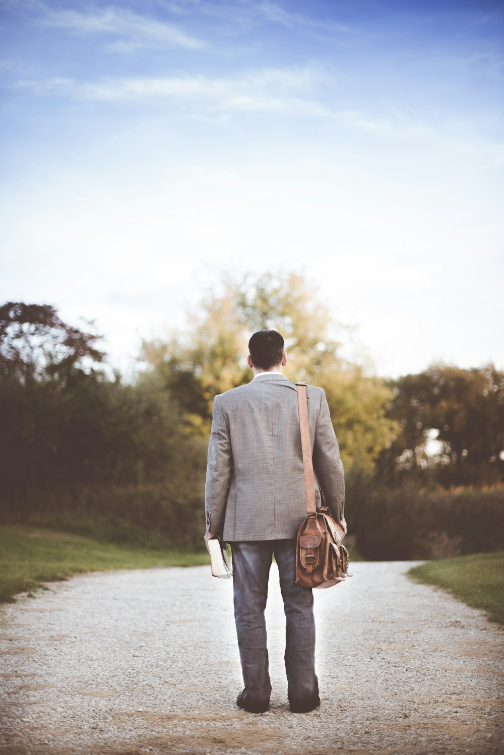 man wearing gray coat standing near road during daytime