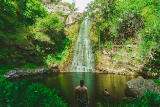 man standing in front of waterfalls during day time