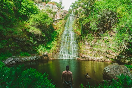 man standing in front of waterfalls during day time