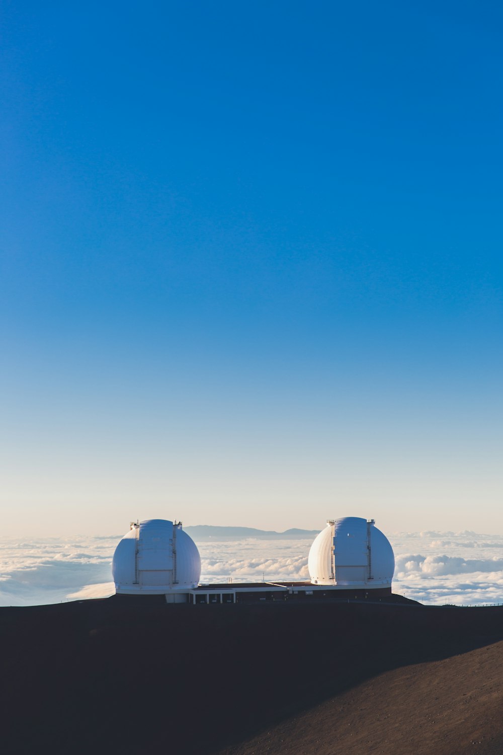 white building on top of mountain with sea of clouds